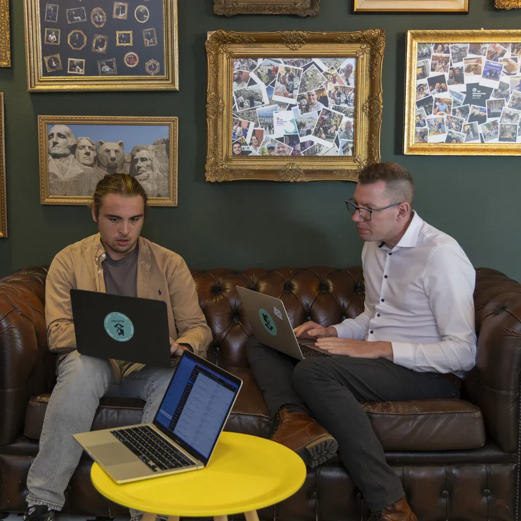 Programmeurs lachen met elkaar voor een bureau op kantoor.