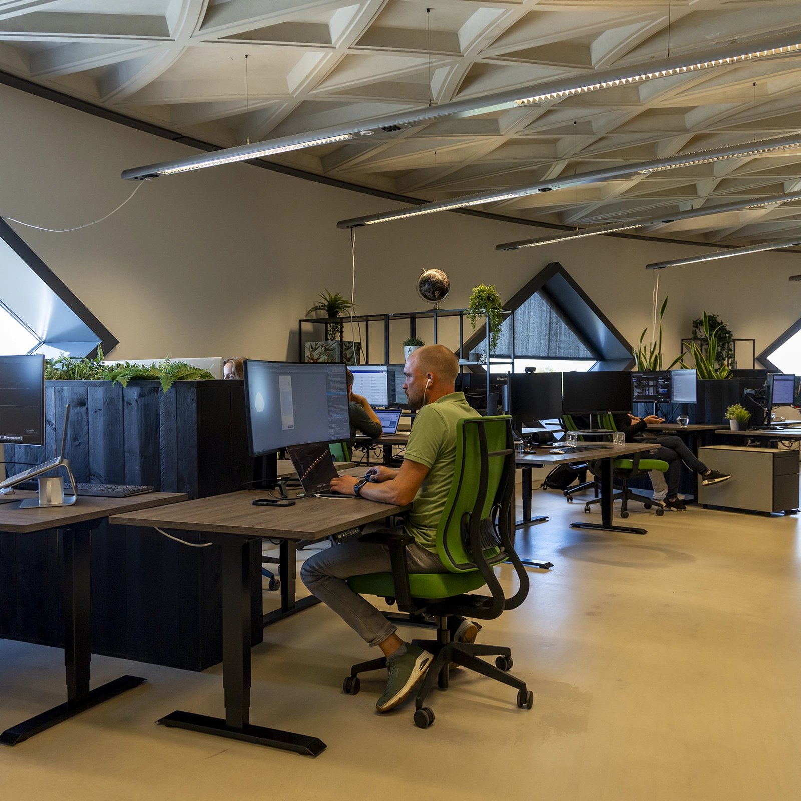 Overzichtsfoto van een van de ruimtes in het kantoor van Sturdy Digital. Op de voorgrond zit een front-end developer te werken aan een WordPress site.