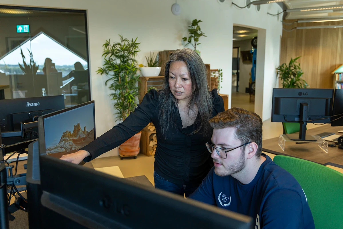 Programmeurs lachen met elkaar voor een bureau op kantoor.