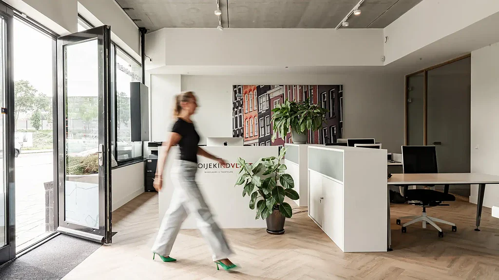 Moderne kantoorreceptie met comfortabele werkplek, groen interieur en entree dankzij glazen deuren voor optimale natuurlijke lichtinval en professionele uitstraling.