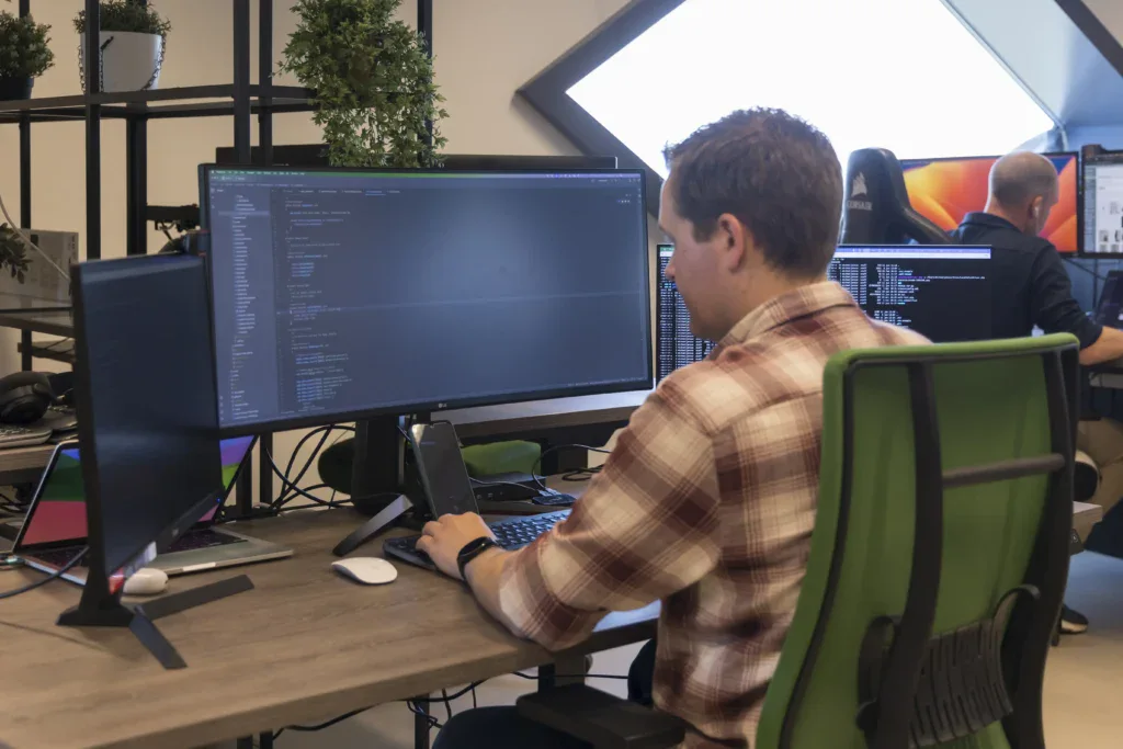 Developer zit achter zijn computer te programmeren op kantoor.