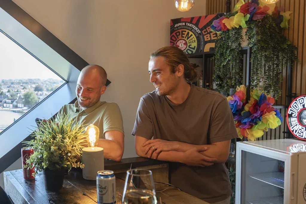 Twee collega's lachen tijdens een borrel op kantoor