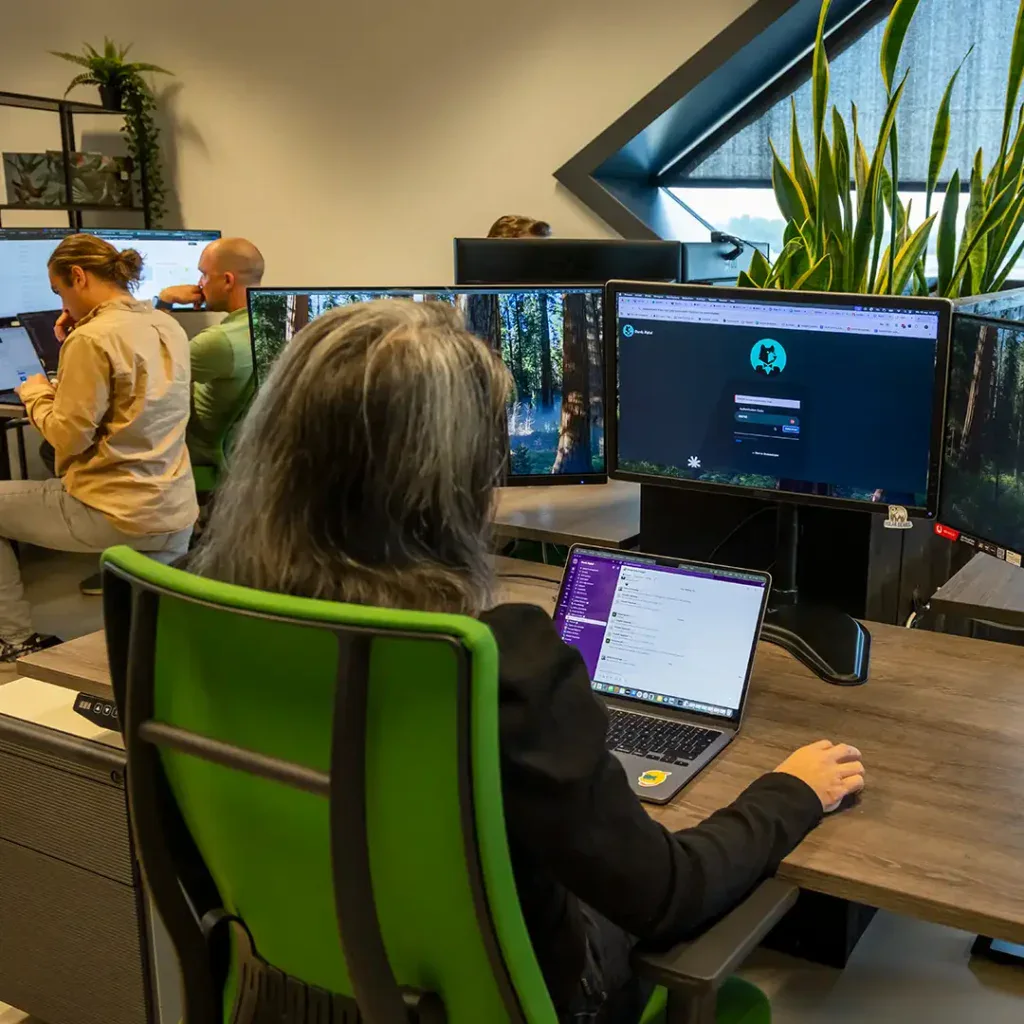 Back end developer is aan het programmeren achter zijn computer op kantoor.