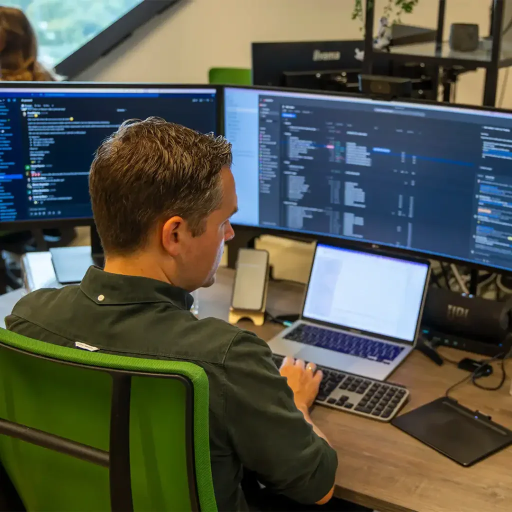 Back end developer is aan het programmeren achter zijn computer op kantoor.