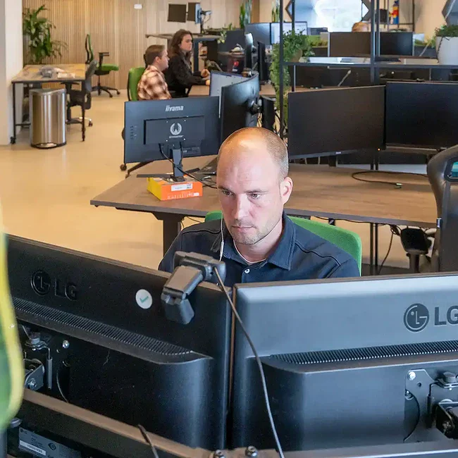 Front end developer zit achter zijn computer te werken op kantoor.